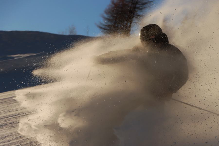Skieur dans un nuage de poudreuse à contre-jour